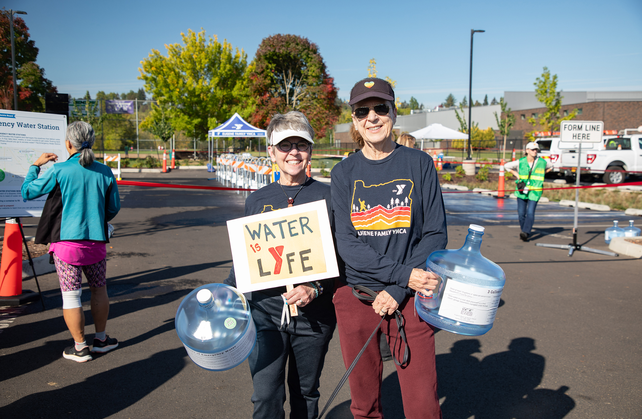 Cedar holds "Water is Lyfe" sign with partner RJ at the Amazon Park Emergency Water Station Demonstration Event