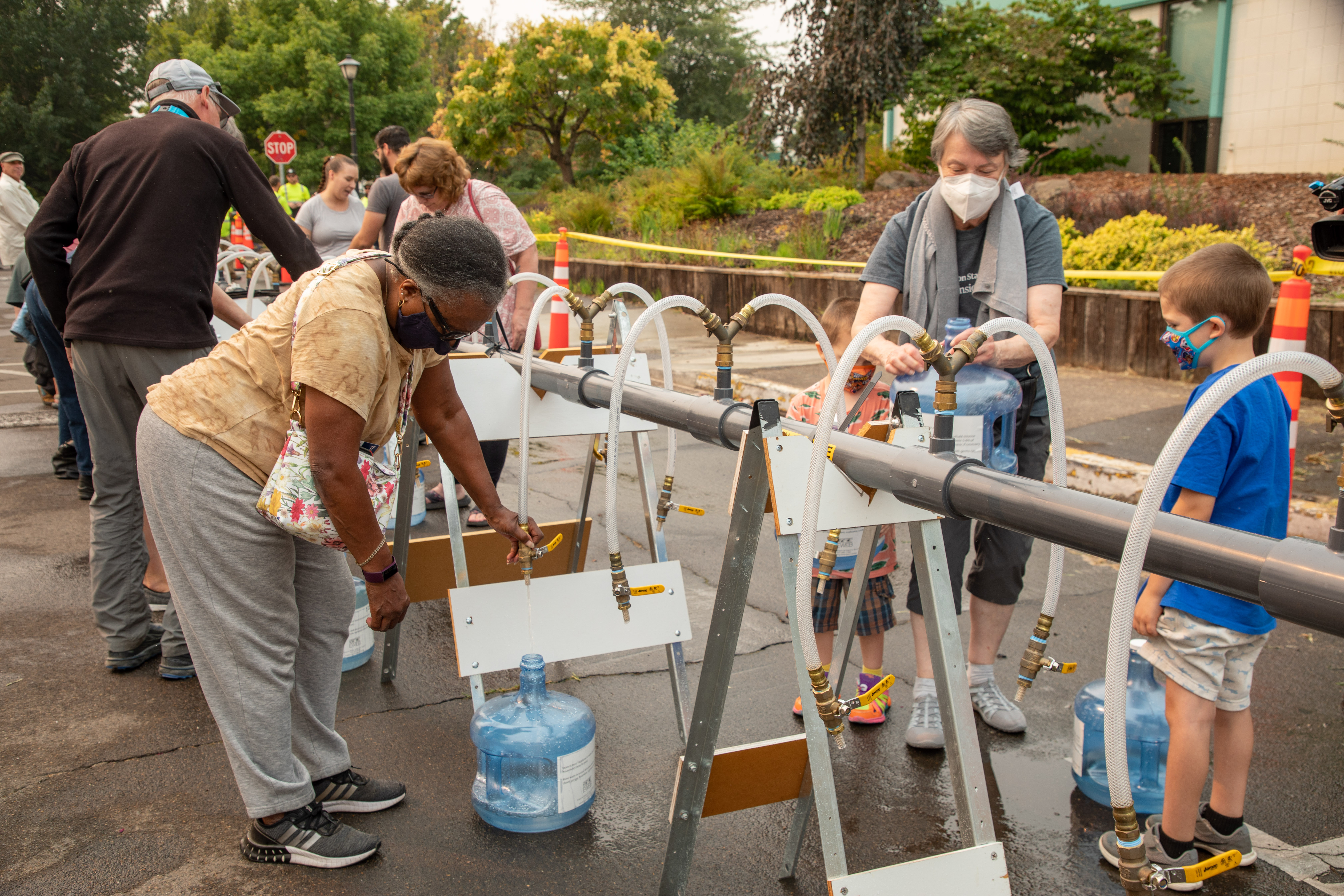 Woman and families filling up water storage containers at a emergency water demonstration event.