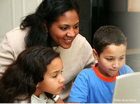 FEMA News Photo: Mother and children looking at a laptop computer