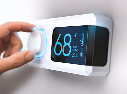 Hand adjusting a smart thermostat set to 68 degrees